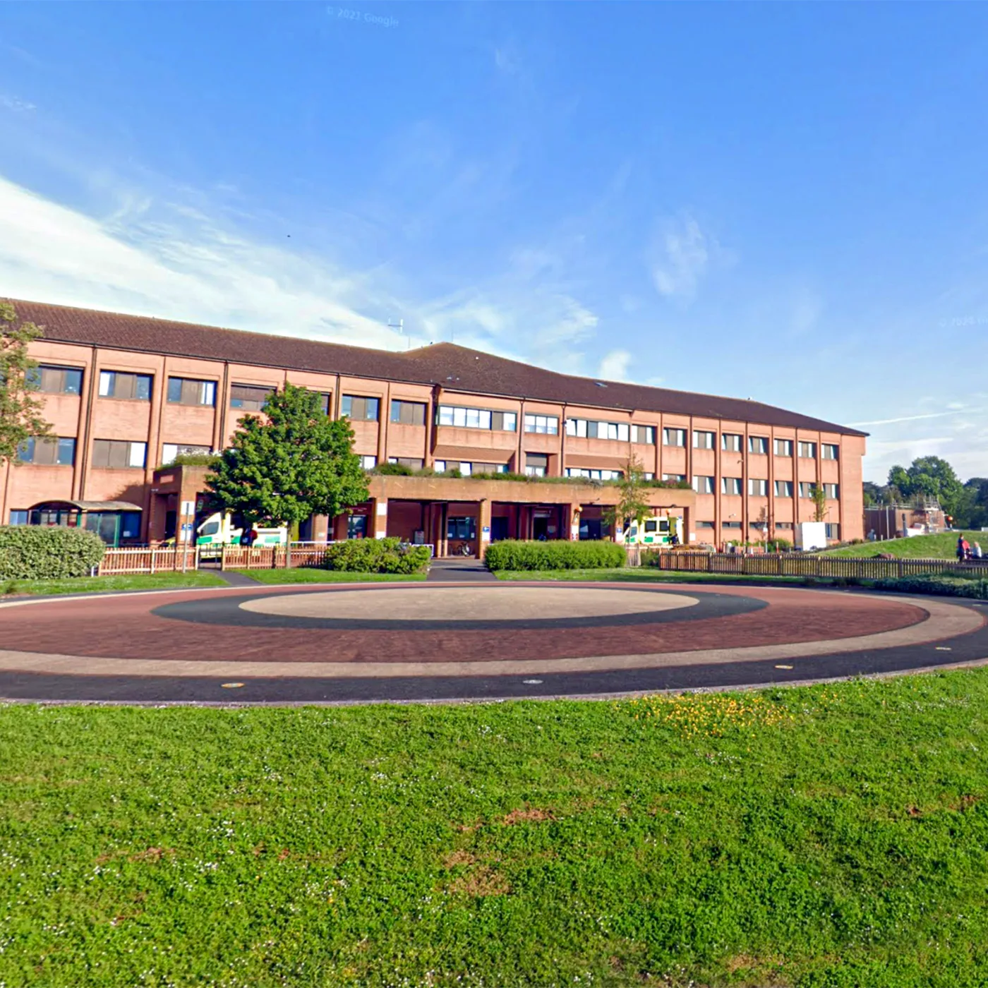 Ein Krankenhausgebäude hinter einer grünen Rasenfläche